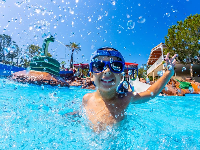 Young boy splashing joyfully in a swimming pool at a vibrant water park, enjoying a sunny summer vacation
