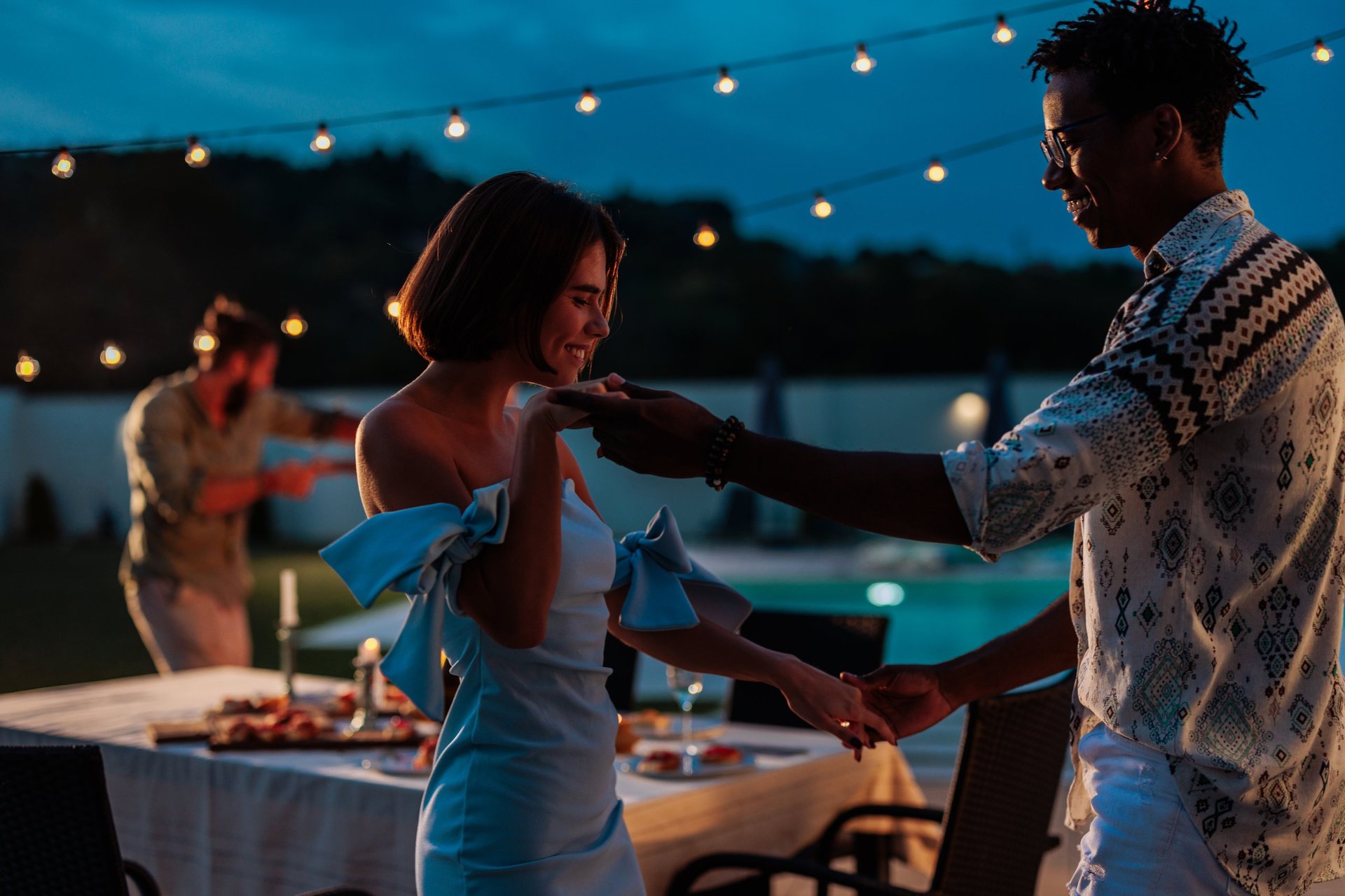 Pareja bailando junto a la piscina durante una fiesta nocturna en un hotel tropical