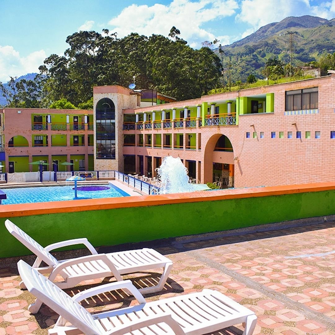 Resort moderno de Antioquia Tropical Club con piscina, edificios coloridos y paisaje montañoso