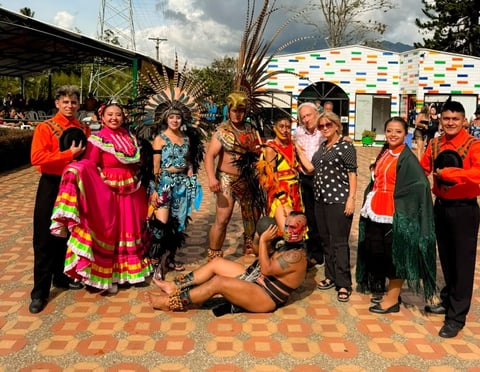 Grupo de personas con coloridos trajes tradicionales indígenas posando juntos en un festival cultural al aire libre