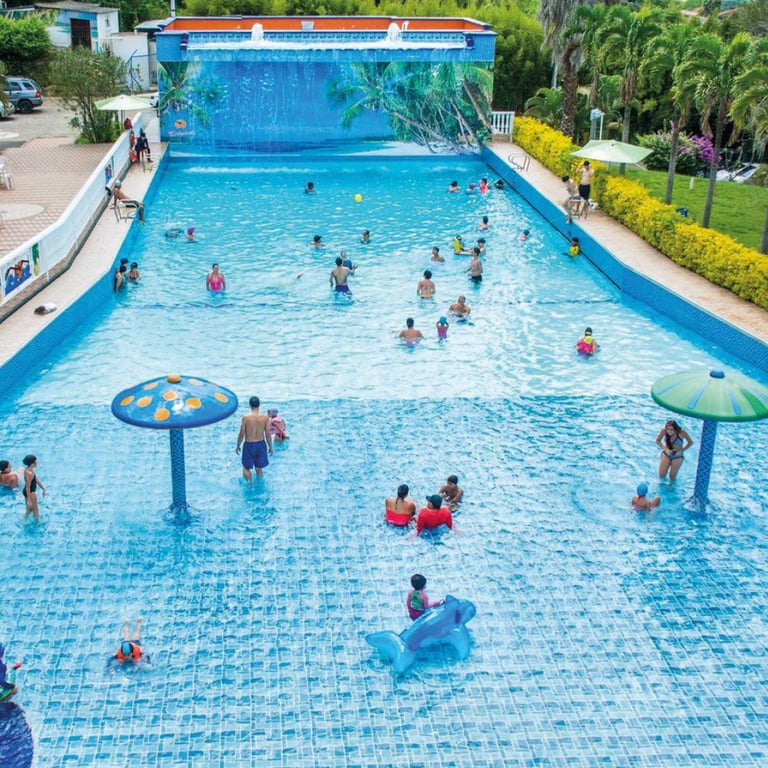 Vista aérea de una piscina pública llena de familias y niños disfrutando del agua en un día soleado