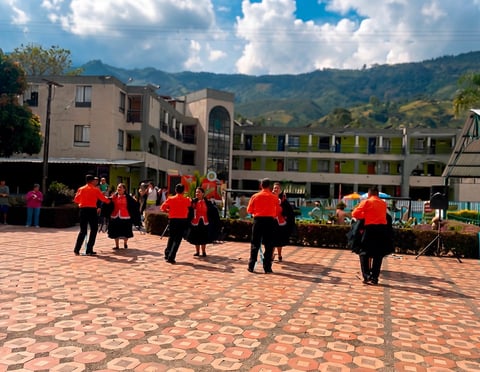 Niños de escuela con uniformes rojos reunidos en un patio de ladrillo con montañas de fondo