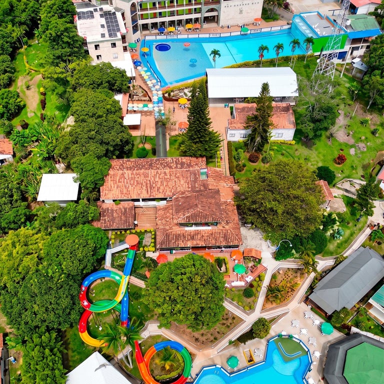 Vista aérea de un parque acuático con varias piscinas, coloridos toboganes de agua y jardines verdes