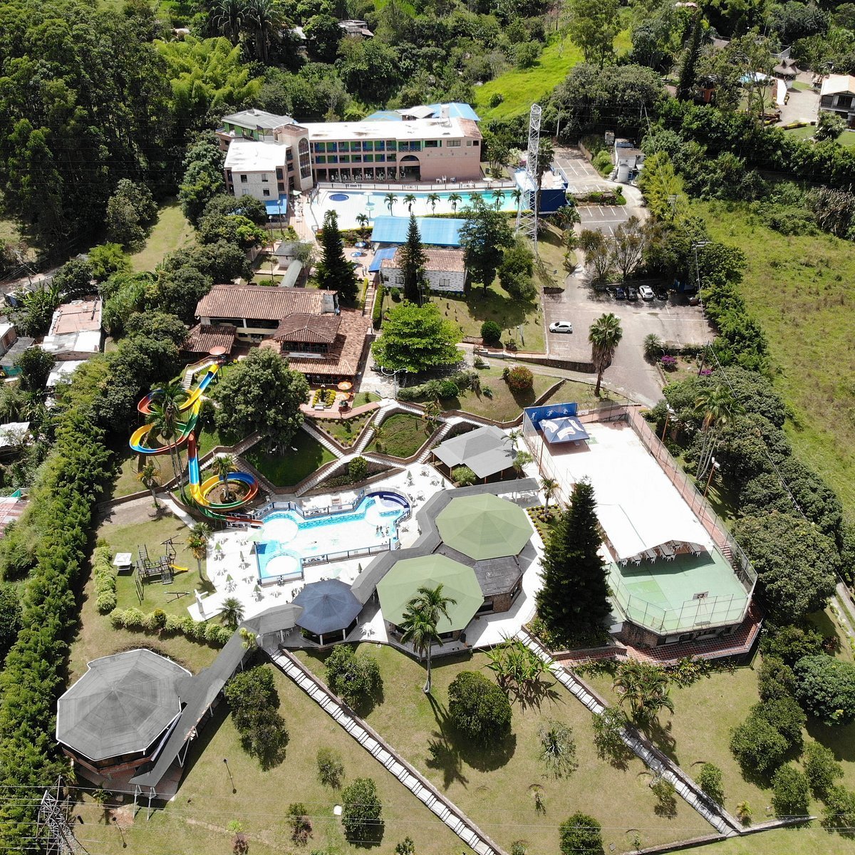 Aerial view of a large resort complex with multiple pools, water slides, recreational facilities, and surrounding green landscaping and trees