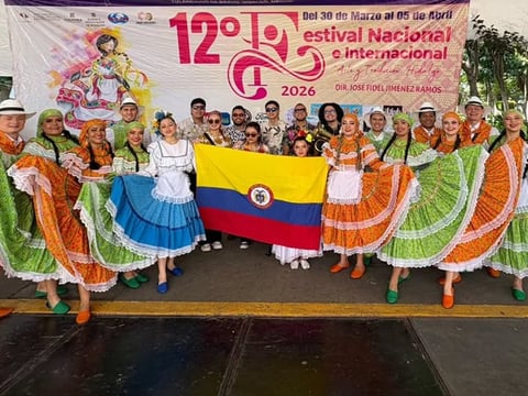 Group of performers in colorful traditional Colombian dress holding the Colombian flag at the 12th National Guabina Festival 2026