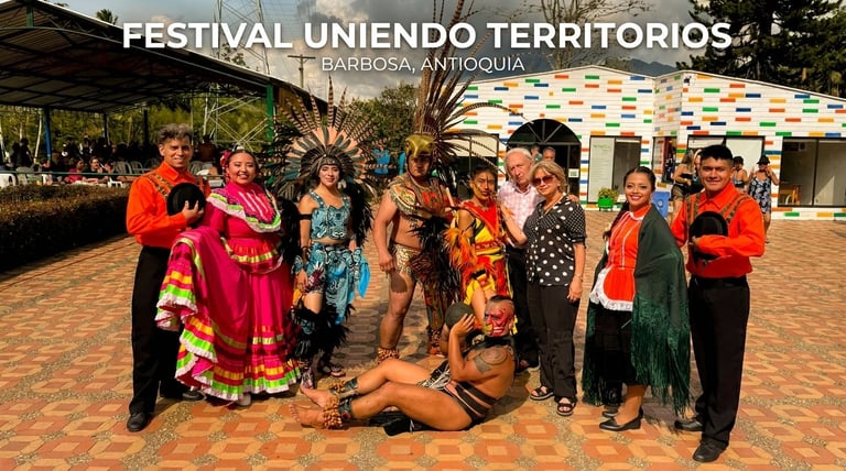 Grupo de personas indígenas con colorida vestimenta tradicional posando juntas en el Festival Uniendo Territorios en Barbosa, Antioquia