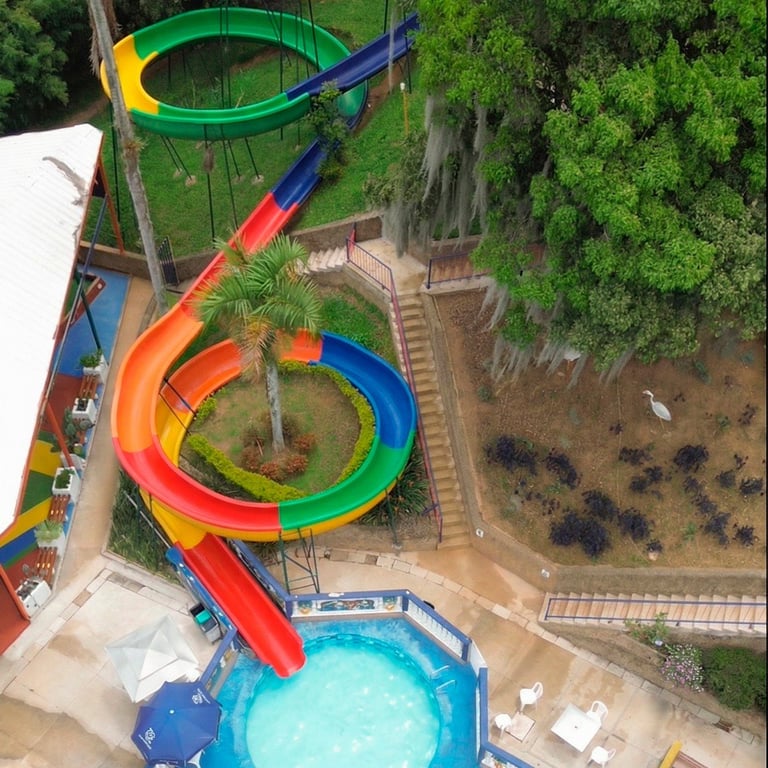 Vista aérea de coloridos toboganes de parque acuático en rojo, naranja, verde y azul que llegan a una piscina
