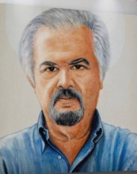 Portrait of a middle-aged man with gray hair, goatee, and mustache wearing a blue shirt against a neutral background