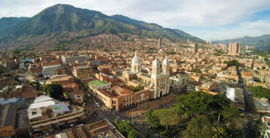 Vista aérea del paisaje urbano de Bello y Medellín con arquitectura colonial, catedral y montañas verdes al fondo